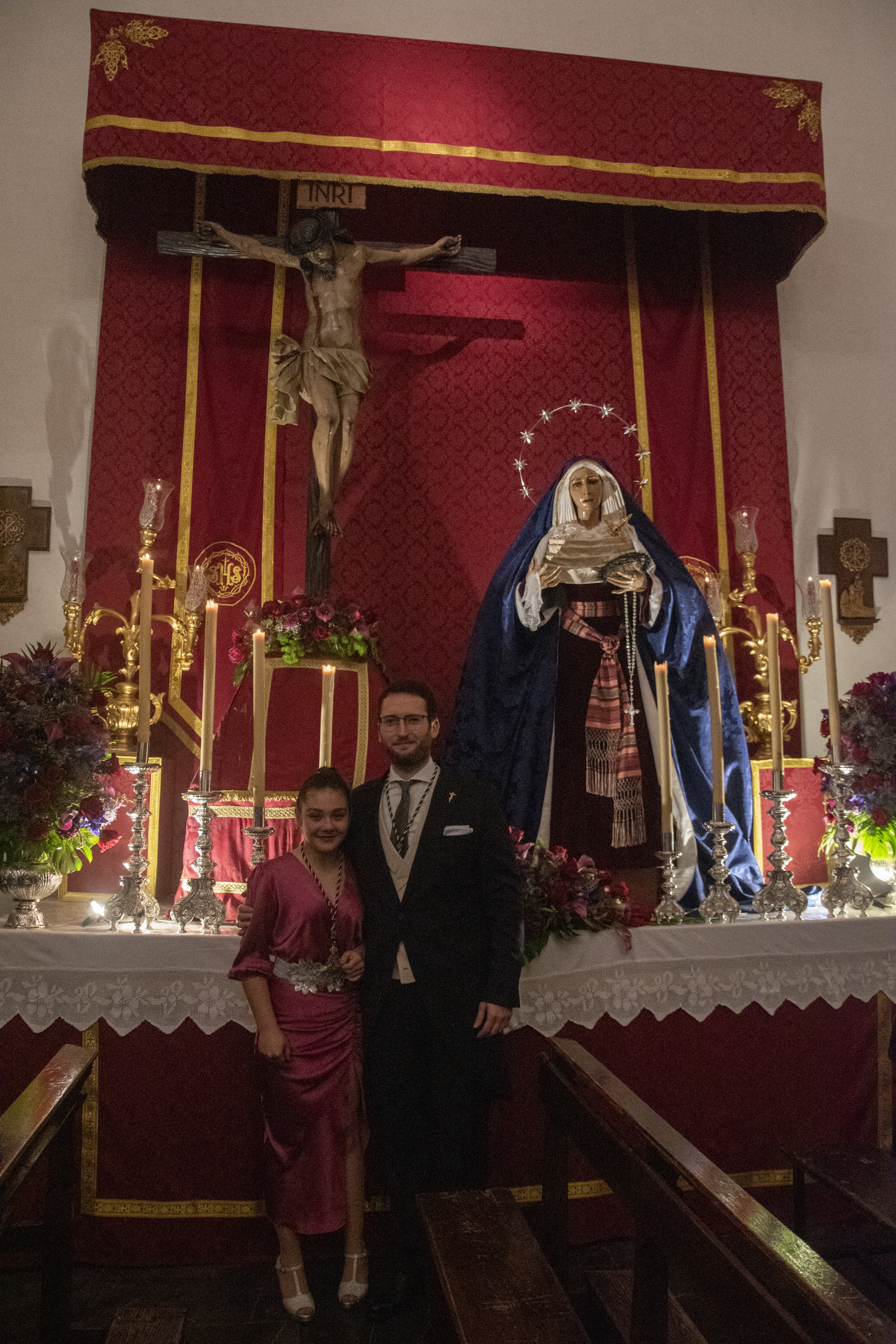 Los pregoneros de 2022, Juan Luque y Teresa Guerra, posan delante del Cristo de la Vera+Cruz y la Virgen de los Dolores.